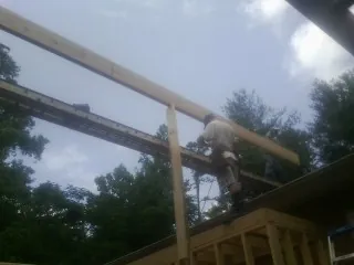 Carpenter setting a ridge beam over a new addition frame — Ice Dam Removal by Roofing Brothers in Clemons