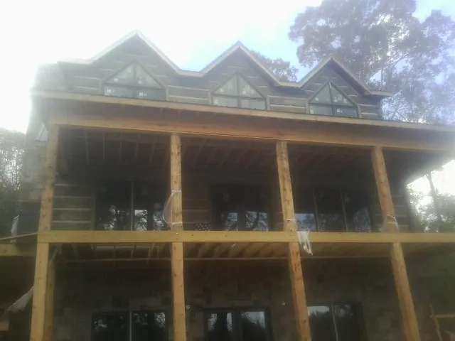 Dormers and porch framing on a large log home under construction — Roof Coating work by our crew in Clemons