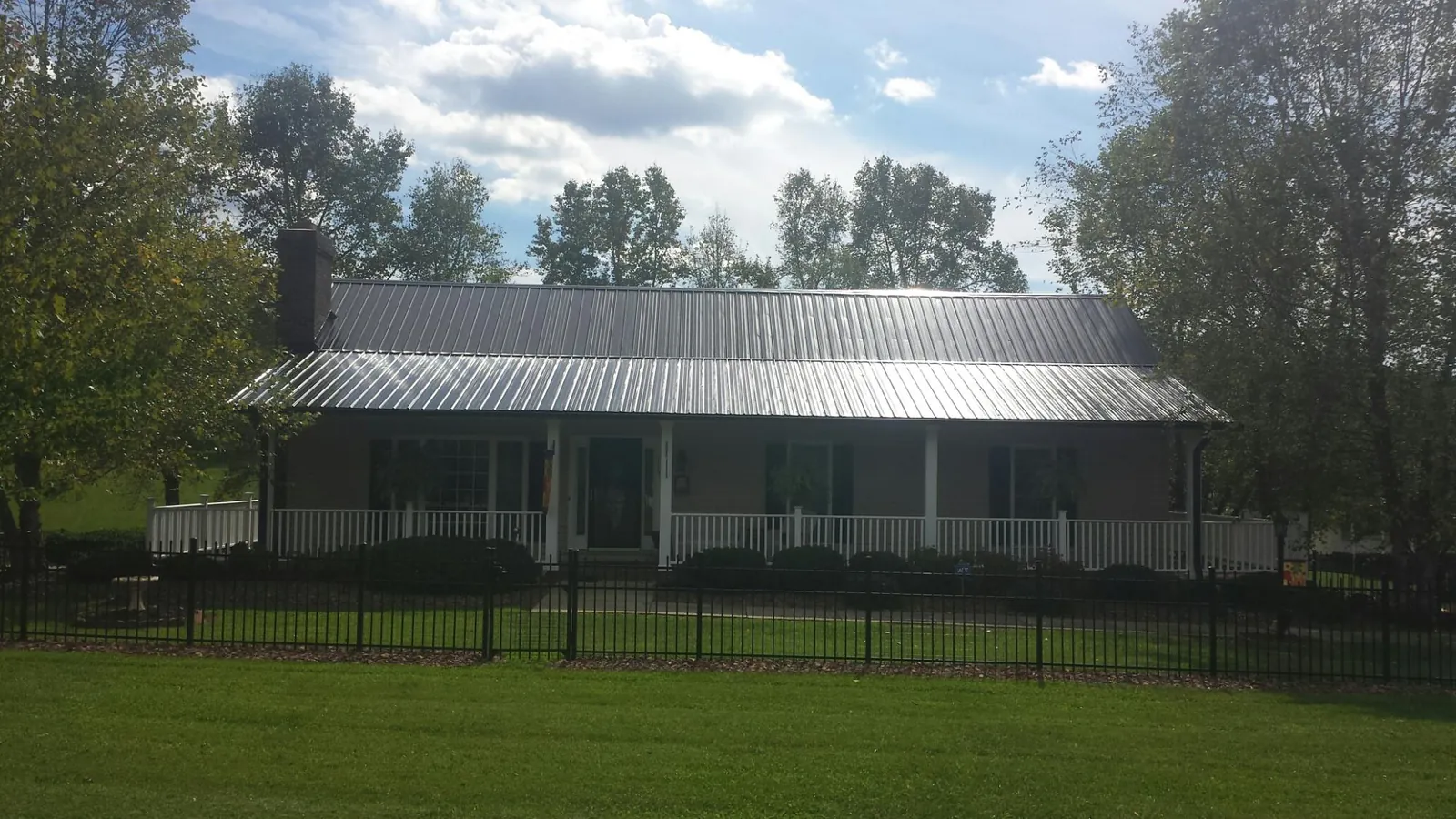 Gray metal roof on a brick ranch with a full width front porch — Gutter Guard Installation work by our crew in Clemons