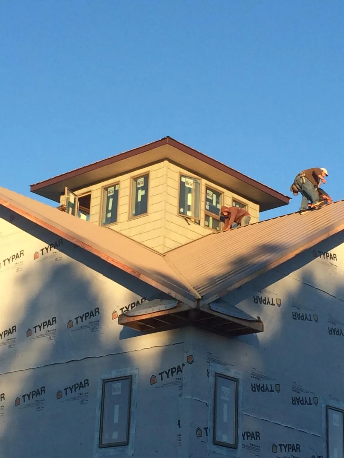 Roofers working around a rooftop cupola on a new metal roof at sunset — Roof Waterproofing in Clemons by Roofing Brothers
